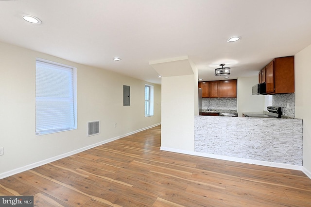 kitchen featuring electric range, light hardwood / wood-style flooring, electric panel, and tasteful backsplash