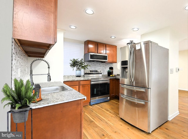 kitchen with tasteful backsplash, light hardwood / wood-style flooring, stainless steel appliances, and sink