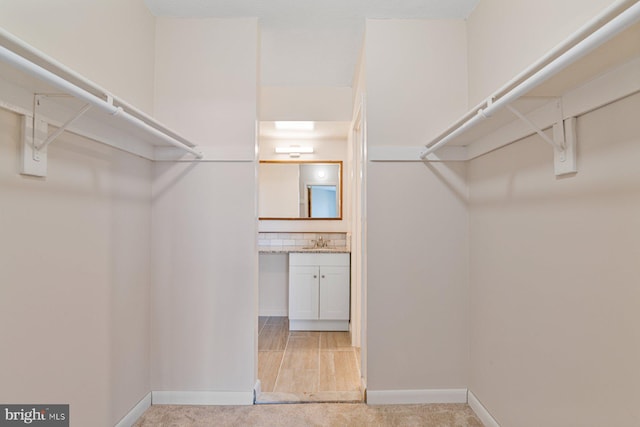 walk in closet featuring light colored carpet and a sink