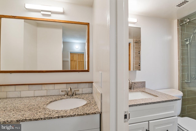 full bathroom with visible vents, toilet, two vanities, and a sink