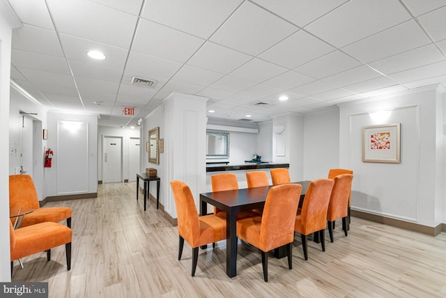 dining room with visible vents, baseboards, recessed lighting, a drop ceiling, and light wood-style floors