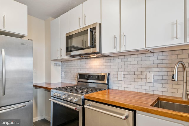 kitchen featuring a sink, wood counters, backsplash, stainless steel appliances, and white cabinets