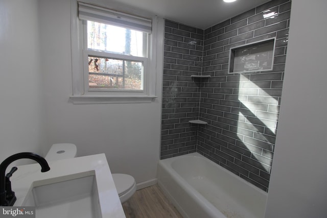 full bathroom featuring hardwood / wood-style flooring, tiled shower / bath combo, toilet, and sink