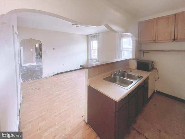 kitchen with light hardwood / wood-style floors, kitchen peninsula, and sink