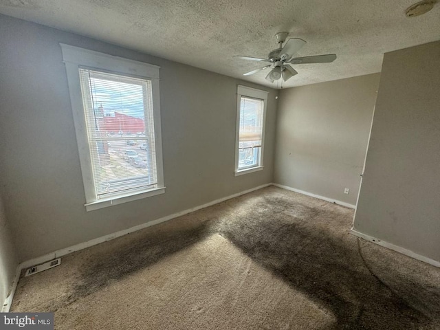 carpeted spare room featuring a textured ceiling and ceiling fan