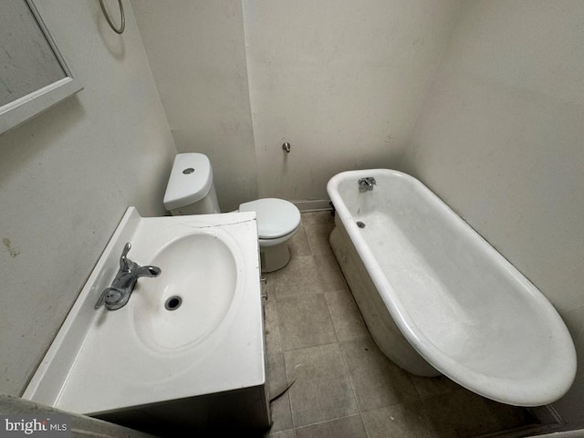 bathroom with a tub to relax in, sink, tile patterned flooring, and toilet