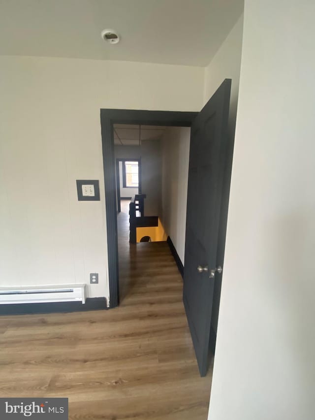 corridor featuring baseboard heating and hardwood / wood-style floors