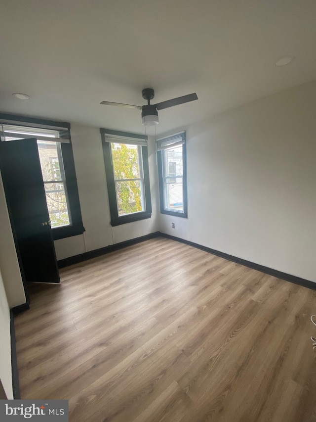 spare room with wood-type flooring, a wealth of natural light, and ceiling fan