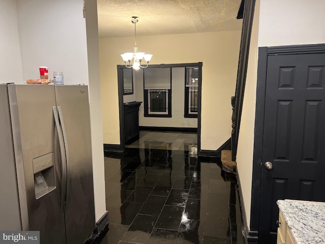 kitchen featuring hanging light fixtures, a textured ceiling, a notable chandelier, light stone counters, and stainless steel fridge with ice dispenser