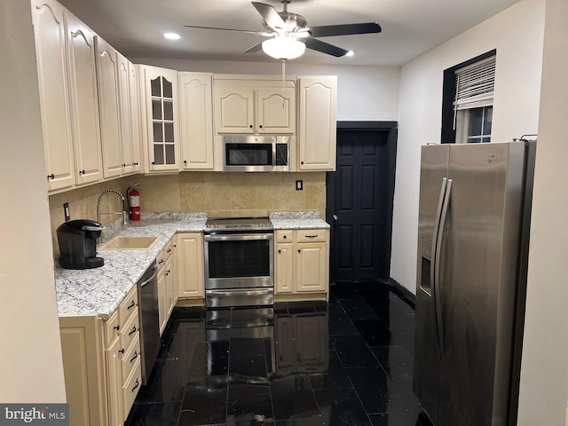 kitchen with ceiling fan, sink, light stone countertops, tasteful backsplash, and appliances with stainless steel finishes