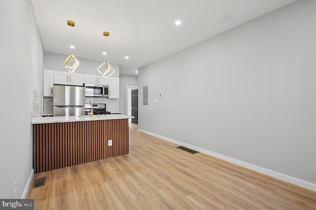 kitchen with white cabinetry, tasteful backsplash, light hardwood / wood-style flooring, pendant lighting, and appliances with stainless steel finishes