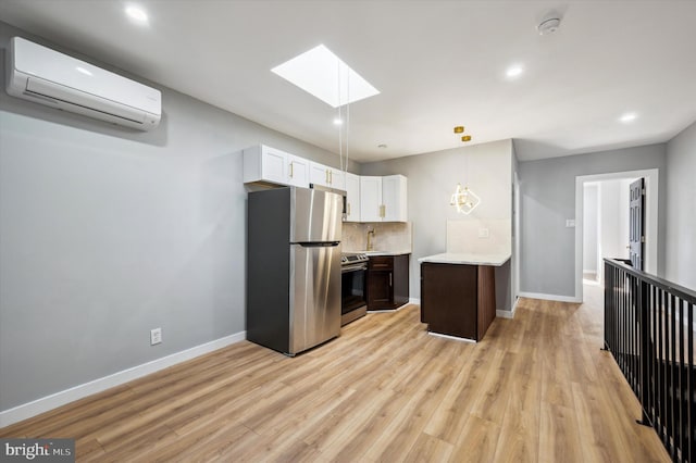 kitchen with white cabinets, appliances with stainless steel finishes, light hardwood / wood-style flooring, and a wall mounted AC