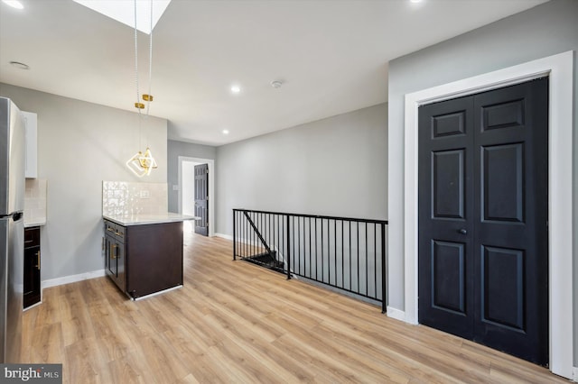 kitchen featuring pendant lighting, dark brown cabinets, and light wood-type flooring