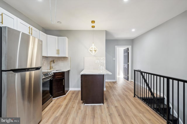 kitchen featuring white cabinets, light hardwood / wood-style floors, appliances with stainless steel finishes, and pendant lighting