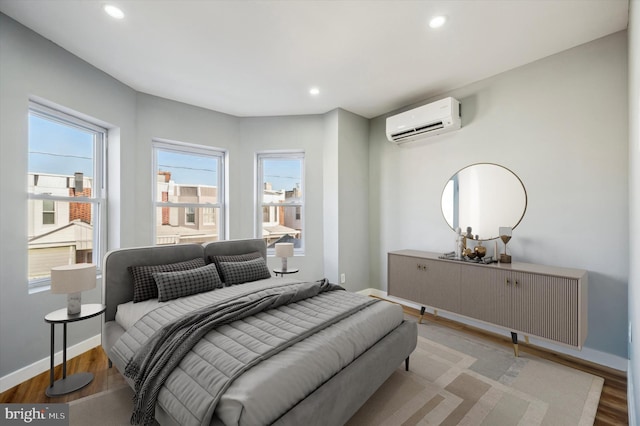 bedroom featuring hardwood / wood-style flooring and a wall unit AC