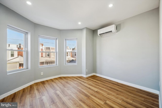 spare room with an AC wall unit and light hardwood / wood-style flooring