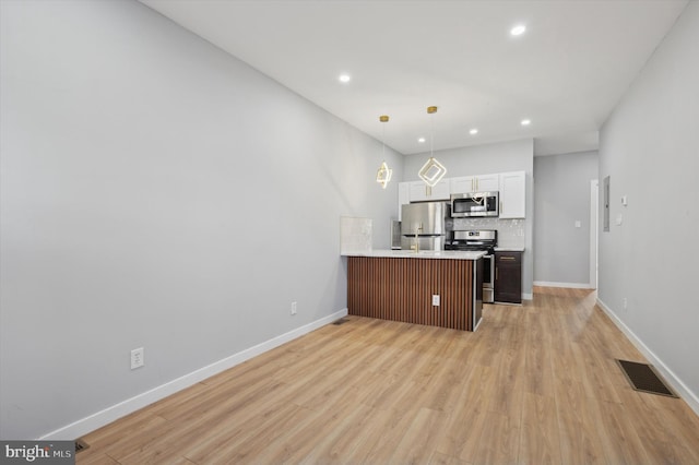 kitchen with kitchen peninsula, appliances with stainless steel finishes, light wood-type flooring, and white cabinetry