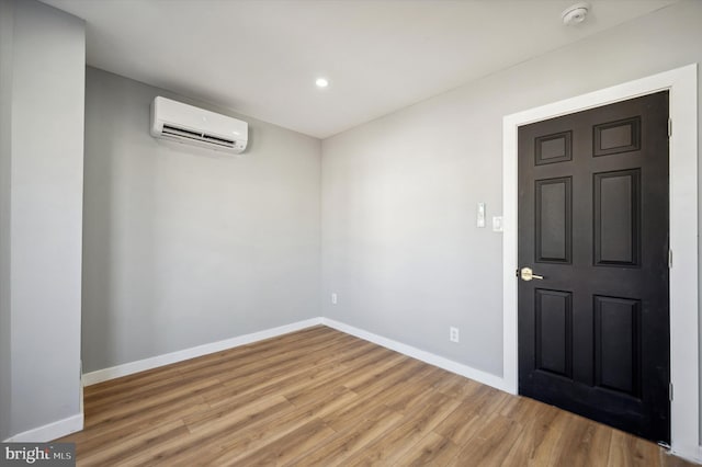 empty room with light hardwood / wood-style flooring and an AC wall unit