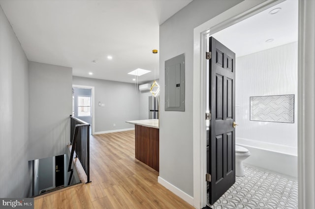 hall featuring electric panel, a wall mounted air conditioner, and light wood-type flooring