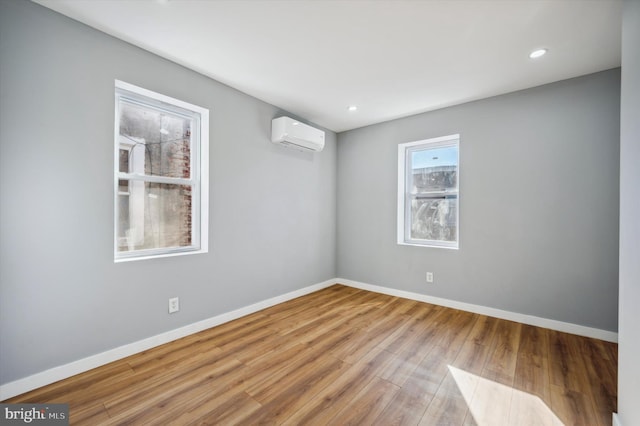 unfurnished room featuring light hardwood / wood-style flooring and an AC wall unit