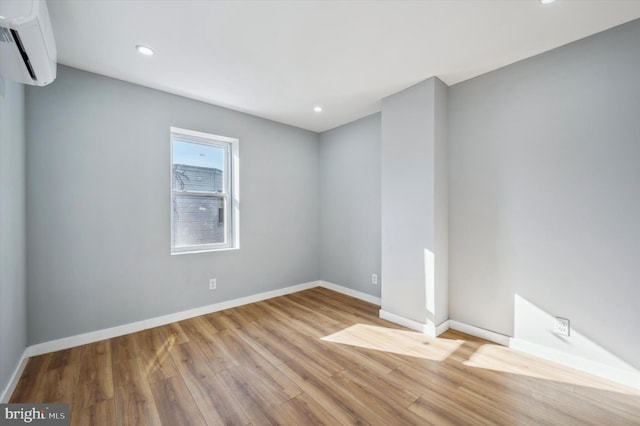 unfurnished room featuring light wood-type flooring and a wall unit AC