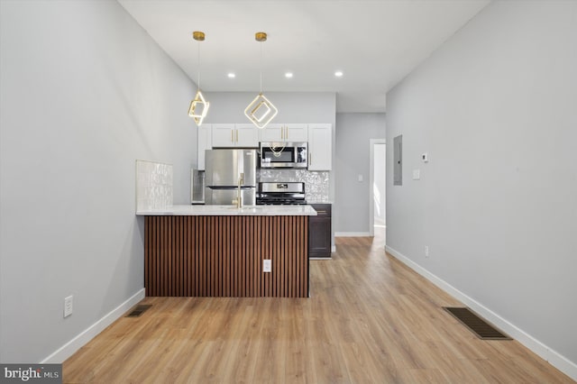 kitchen featuring hanging light fixtures, white cabinetry, light hardwood / wood-style flooring, and stainless steel appliances