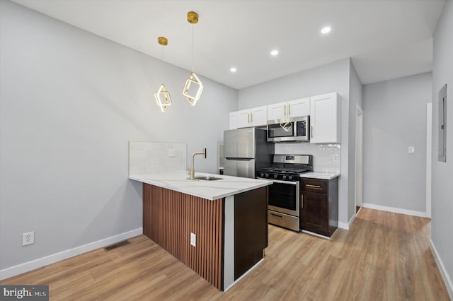 kitchen featuring sink, stainless steel appliances, kitchen peninsula, light hardwood / wood-style floors, and decorative light fixtures