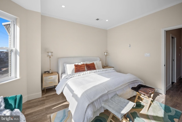 bedroom with dark hardwood / wood-style flooring, ornamental molding, and multiple windows