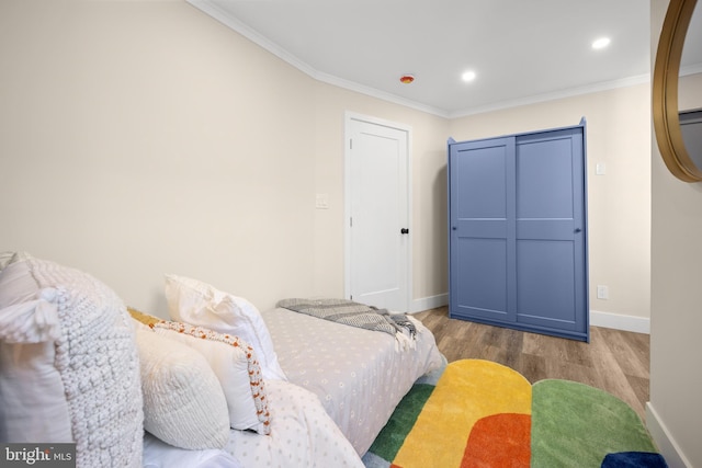 bedroom with hardwood / wood-style flooring, ornamental molding, and a closet