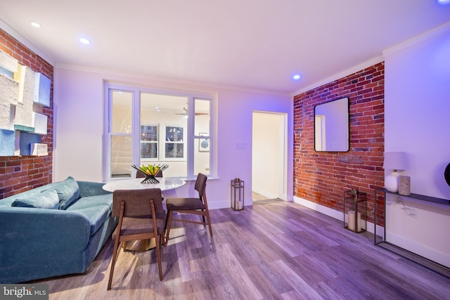 living room featuring crown molding, wood-type flooring, and brick wall