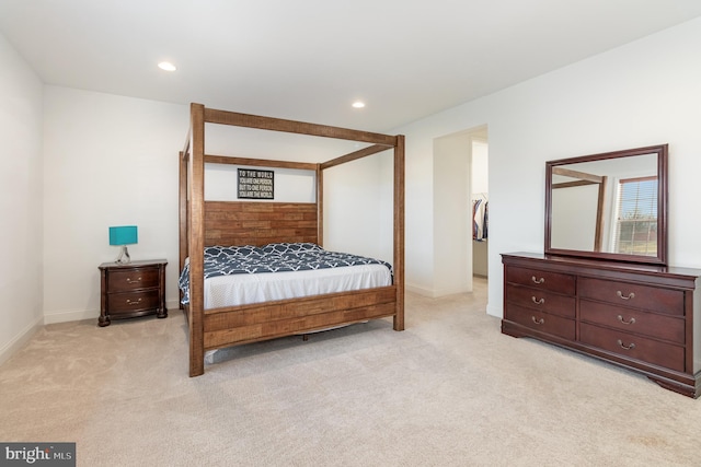 bedroom featuring a spacious closet, a closet, and light colored carpet