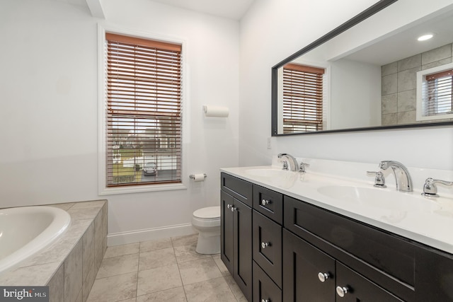 bathroom featuring tile patterned flooring, vanity, toilet, and tiled bath