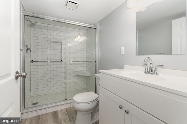 bathroom with hardwood / wood-style floors, vanity, toilet, and walk in shower