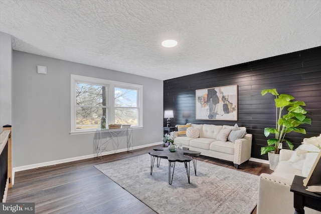 living room with a textured ceiling, dark hardwood / wood-style flooring, and wooden walls