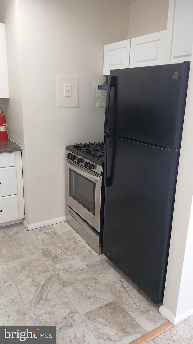 kitchen featuring black fridge, white cabinets, and stainless steel gas range