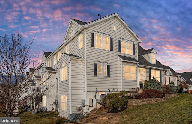 property exterior at dusk with central air condition unit and a yard