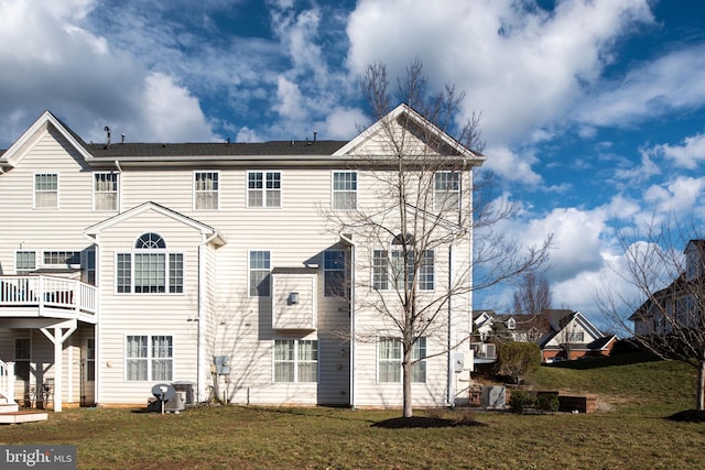 rear view of property featuring a lawn and central air condition unit