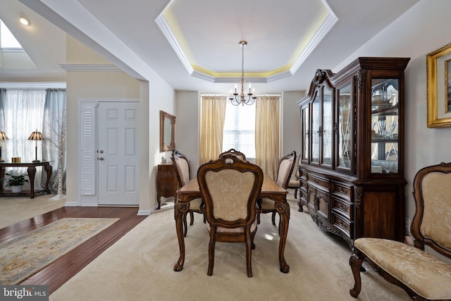 dining space with hardwood / wood-style flooring, a raised ceiling, crown molding, and a chandelier