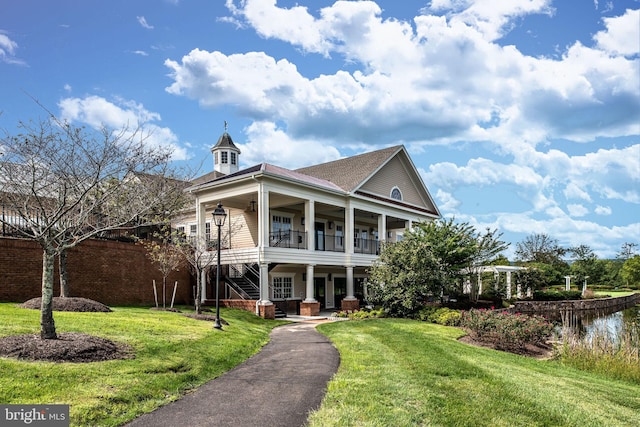 neoclassical home featuring covered porch, a balcony, and a front lawn