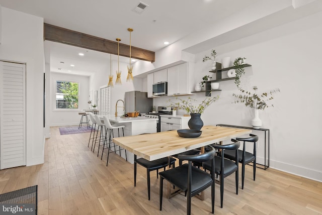 dining area with beam ceiling and light wood-type flooring