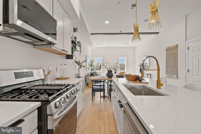 kitchen featuring white cabinets, sink, light wood-type flooring, light stone counters, and stainless steel appliances