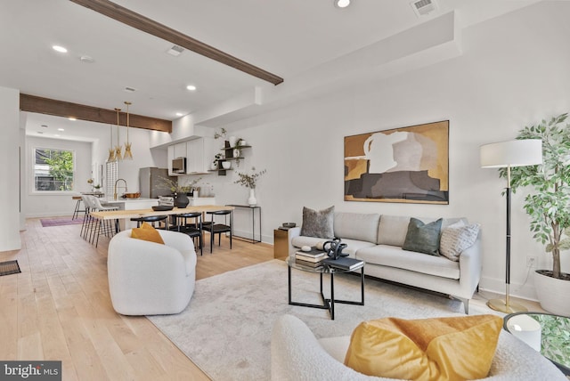 living room featuring beam ceiling and light hardwood / wood-style flooring