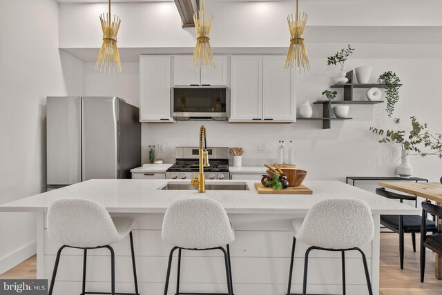 kitchen featuring light stone countertops, a kitchen breakfast bar, light wood-type flooring, stainless steel appliances, and white cabinetry