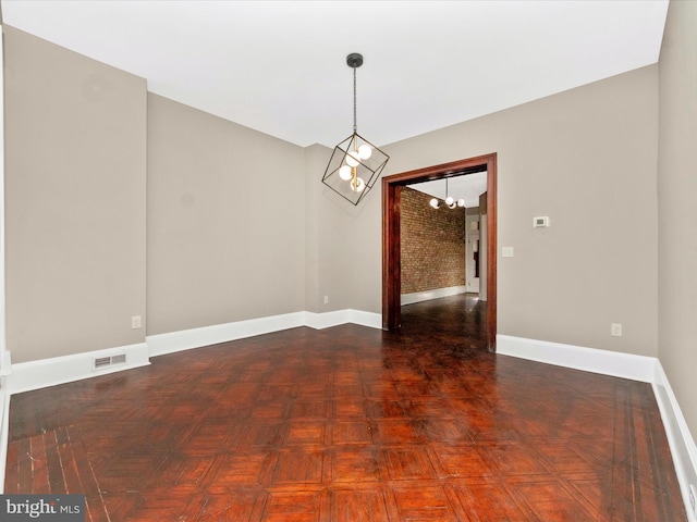 unfurnished dining area with dark parquet floors, brick wall, and an inviting chandelier