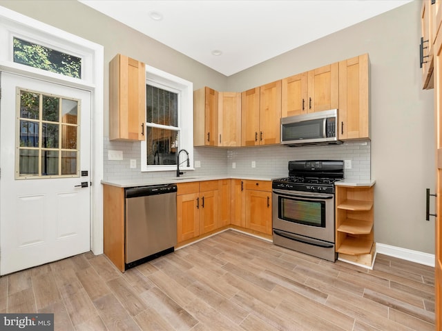 kitchen featuring light brown cabinets, backsplash, sink, light hardwood / wood-style flooring, and appliances with stainless steel finishes