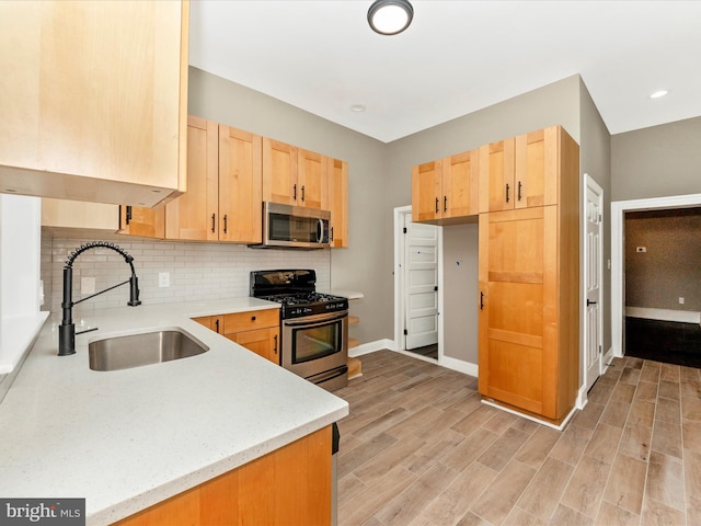310 E 25th St, Baltimore, MD 21218 - kitchen with stainless steel appliances, a sink, light brown cabinetry, light wood-type flooring, and decorative backsplash