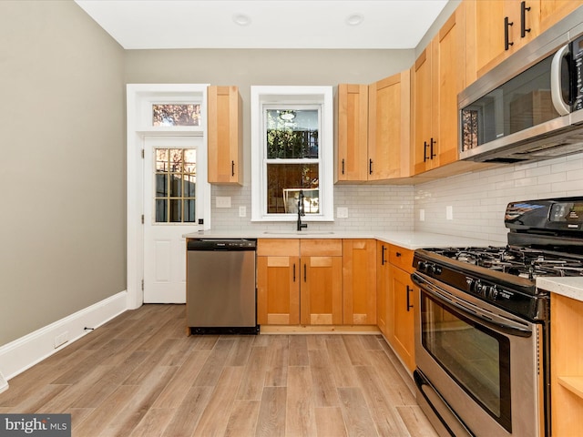 kitchen featuring sink, light brown cabinets, stainless steel appliances, light hardwood / wood-style flooring, and backsplash