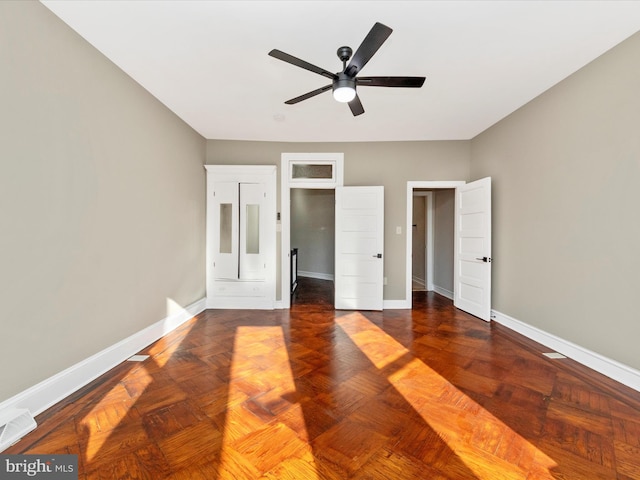 unfurnished bedroom with dark parquet flooring and ceiling fan