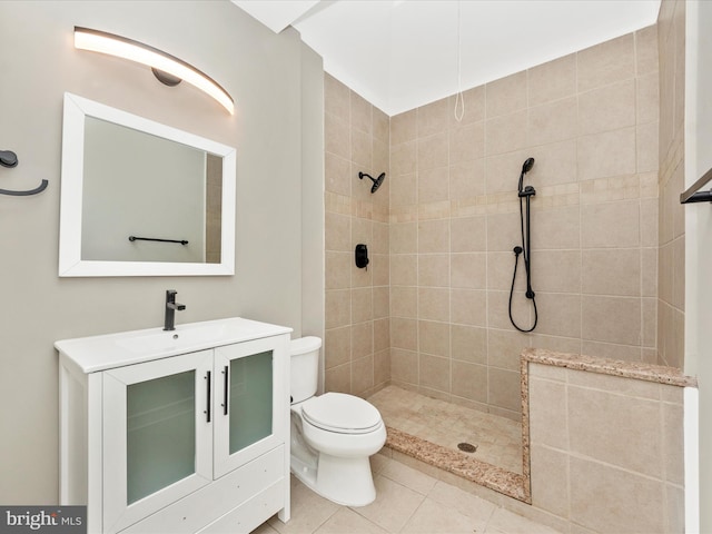 bathroom with tiled shower, vanity, tile patterned flooring, and toilet