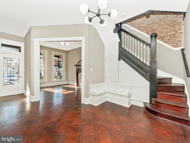 stairway featuring a notable chandelier, parquet floors, and vaulted ceiling